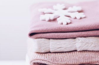 a stack of folded sweaters with a snowflake on top